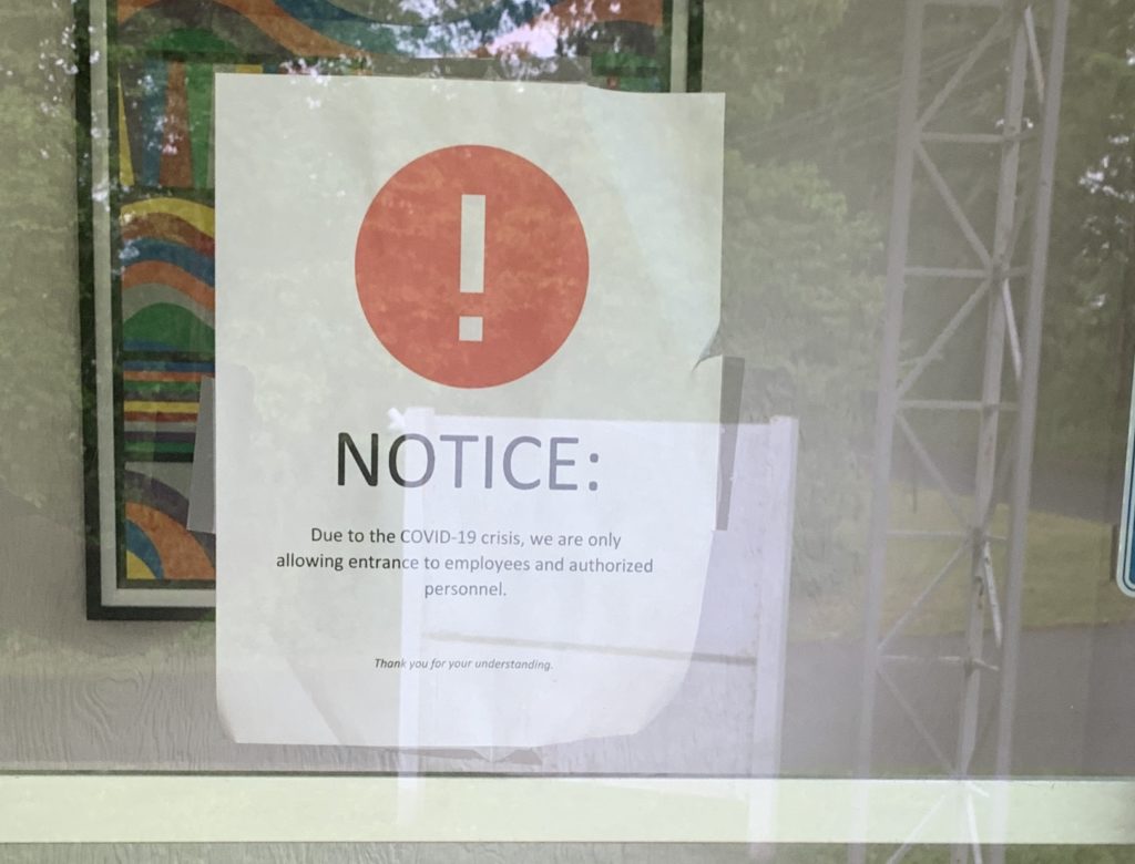covid 19 notice on an office door that only allows authorized entrants