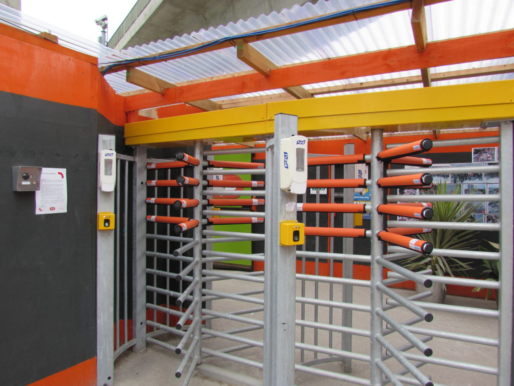 full height turnstile with orange padded safety sleeves at head and arm level