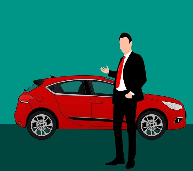 car dealer motioning with his hand towards a red car