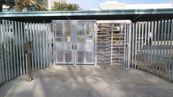 full height turnstile and full height ada gate integrated into an entry fenceline at a facility in galvanized silver