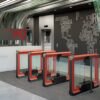 row of red custom colored optical turnstiles in an office lobby with swinging glass barriers