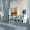 rows of optical turnstiles with swinging glass barriers in an open office lobby entrance