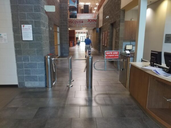 An MR200 ADA turnstile installed at the entrance of Glenwood YMCA, with large windows and a well-lit interior visible in the background.
